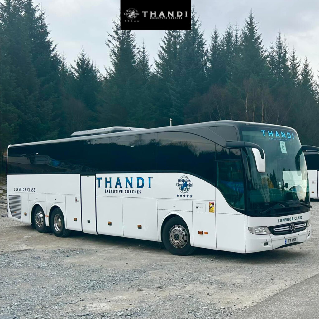 Luxury executive coach bus parked roadside with festive holiday decorations.